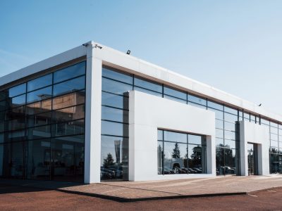 Modern car building. Many vehicles inside. Sunny day with clear sky.